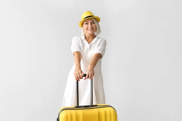 Mature woman with suitcase on light background — Stock Photo, Image