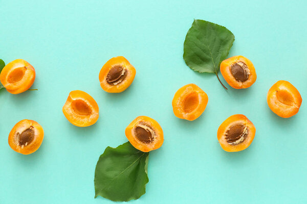 Tasty cut apricots on color background