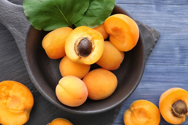 Frying pan with tasty apricots on wooden background — Stock Photo, Image
