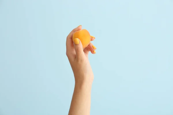 Female hand with tasty apricot on light background — Stock Photo, Image