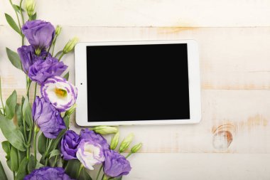 Beyaz ahşap arka plan üzerinde çiçek buketi ile modern tablet bilgisayar