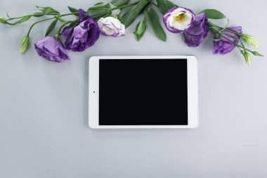 Gri arka planda çiçekleri olan modern tablet bilgisayar