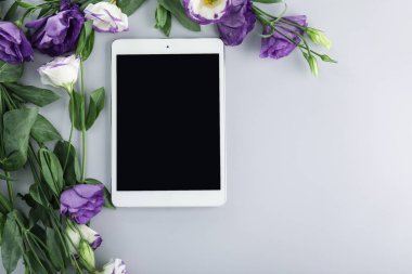 Gri arka planda çiçekleri olan modern tablet bilgisayar