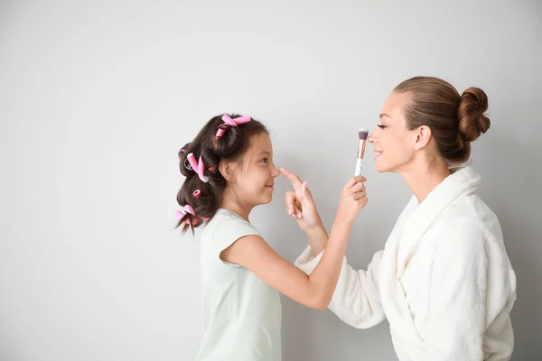 明るい背景から母親の顔に化粧を適用するかわいい小さな娘 — ストック写真