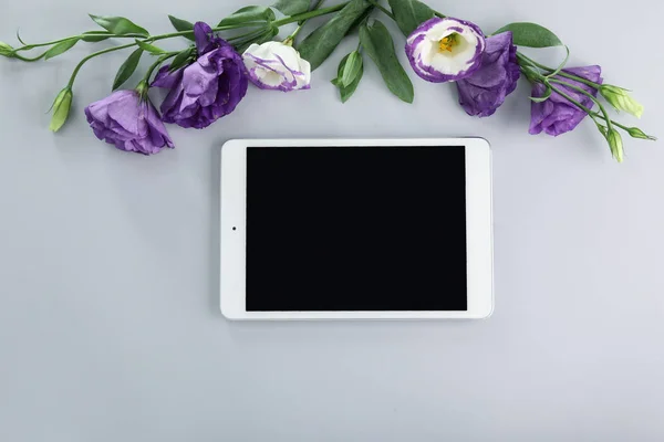 Modern tablet computer with flowers on grey background