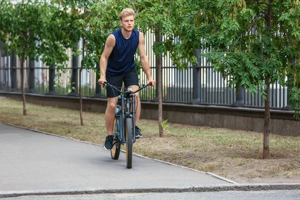 Sporty young man riding bicycle outdoors — Stock Photo, Image