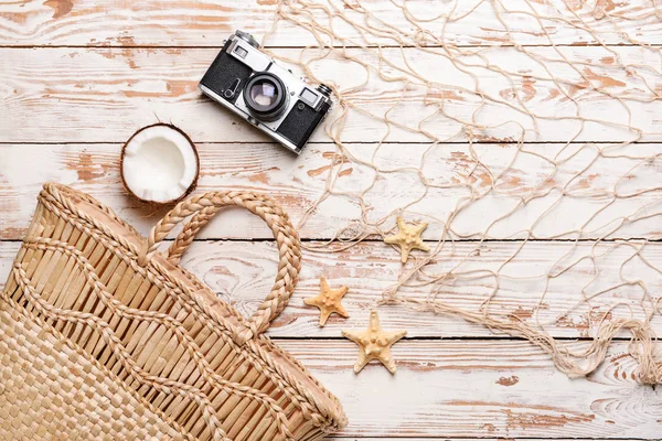 Borsa da spiaggia, macchina fotografica e cocco su sfondo di legno — Foto Stock