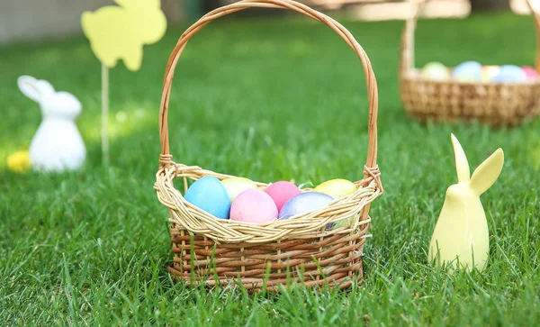 Cesta com ovos de Páscoa e coelho na grama ao ar livre — Fotografia de Stock