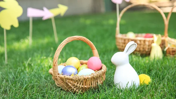 Cesta com ovos de Páscoa e coelho na grama ao ar livre — Fotografia de Stock