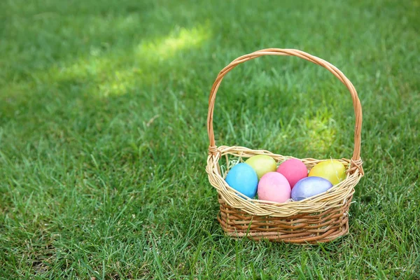 Basket with Easter eggs on grass outdoors — Stock Photo, Image