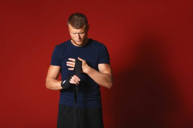 Güçlü erkek boksör renk arka plan üzerinde bileklik uygulayarak