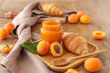 Ahşap masa üzerinde lezzetli kayısı reçeli ve kruvasan ile tabak