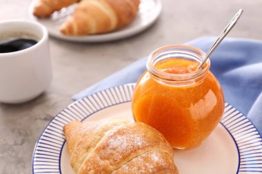 Lezzetli kayısı reçeli ve gri masada kruvasan ile tabak, closeup