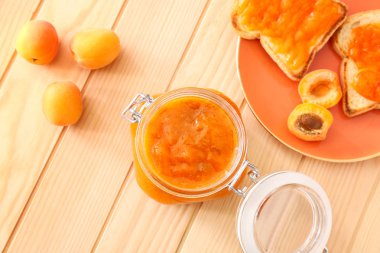 Ahşap masa üzerinde lezzetli kayısı reçeli ve ekmek ile Kavanoz