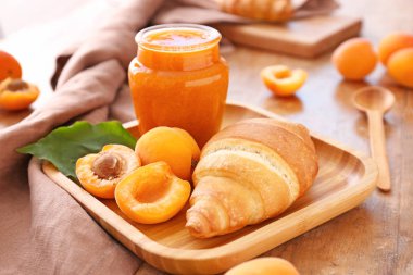 Ahşap masa üzerinde lezzetli kayısı reçeli ve kruvasan ile tabak