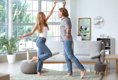 Mutlu genç çift evde dans ediyor.