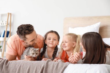 Evde yatakta yatan sevimli kedi ile mutlu aile