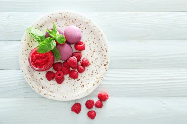 Beyaz ahşap masa üzerinde taze ahududu, reçel ve makarna ile Plaka