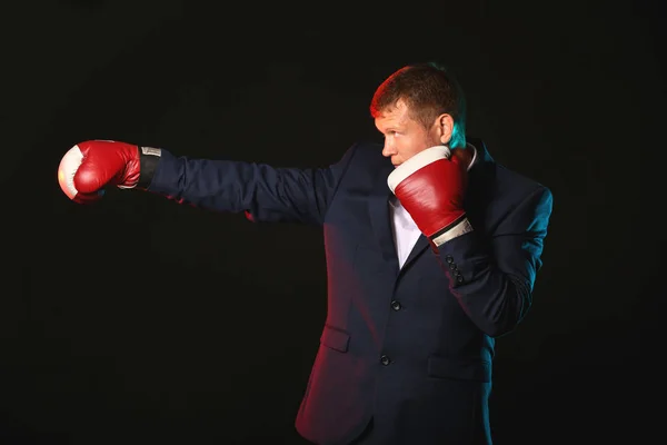 Empresario en guantes de boxeo sobre fondo oscuro — Foto de Stock