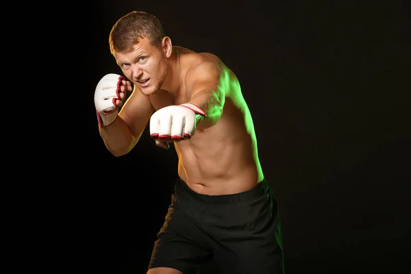 Strong male boxer on dark background