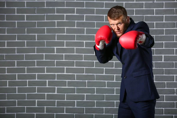 Businessman in boxing gloves against brick wall