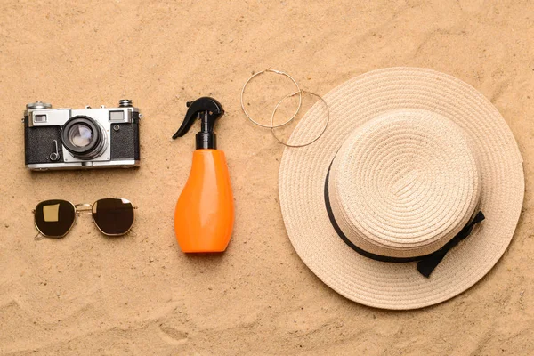 Cámara fotográfica, crema de protección solar, sombrero y gafas de sol sobre arena —  Fotos de Stock