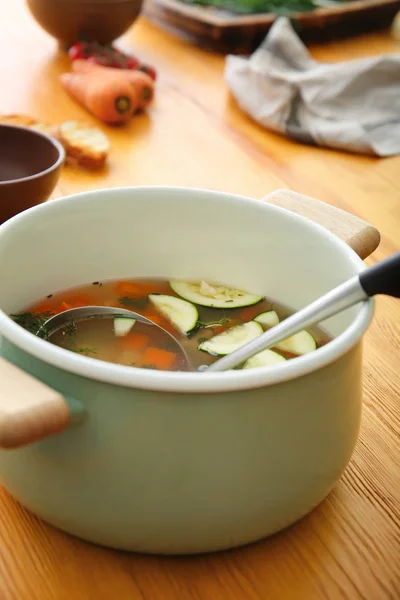 Горшок вкусного супа на деревянном столе — стоковое фото