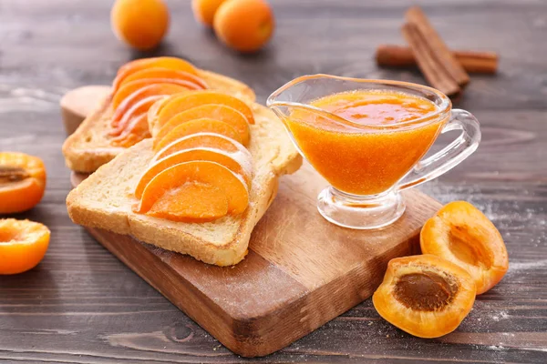 Chlebové plátky s chutnou meruňkové marmeládou na dřevěné desce — Stock fotografie
