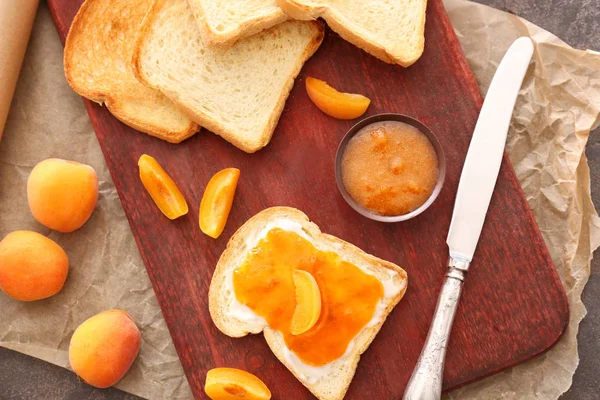 Bowl of tasty apricot jam and bread slices on board — Stock Photo, Image