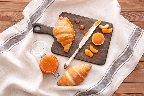 Tasty apricot jam with croissants on table — Stock Photo, Image