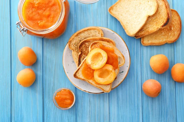 Bread slices of tasty apricot jam on wooden table — Stock Photo, Image