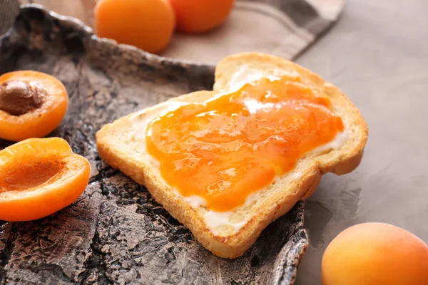 Slice of bread with tasty apricot jam on plate, closeup — Stock Photo, Image