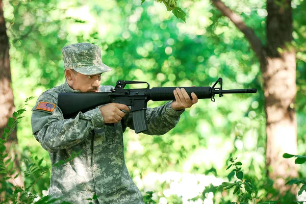 Soldado en camuflaje apuntando en el bosque — Foto de Stock