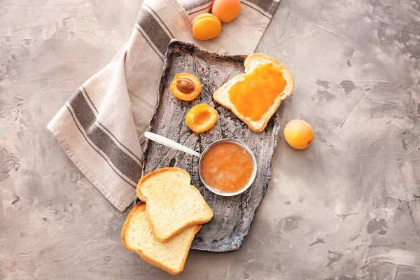 Plate with tasty apricot jam and bread slices on grunge background — Stock Photo, Image