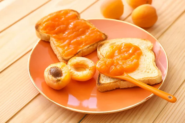 Plate with tasty bread slices and jam on wooden table — Stock Photo, Image