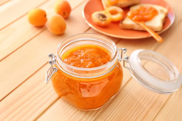 Jar of tasty apricot jam on wooden table — Stock Photo, Image