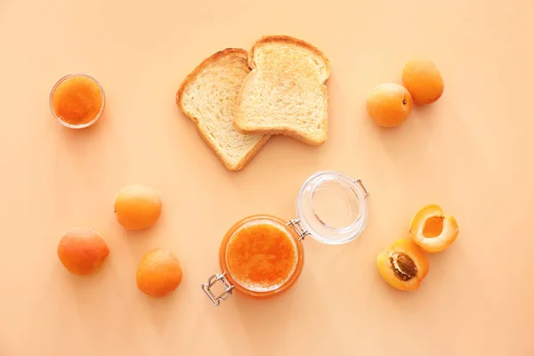 Lahodná meruňková marmeláda s chlebové plátky na barevném pozadí — Stock fotografie
