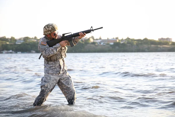 Soldado en camuflaje apuntando en río — Foto de Stock
