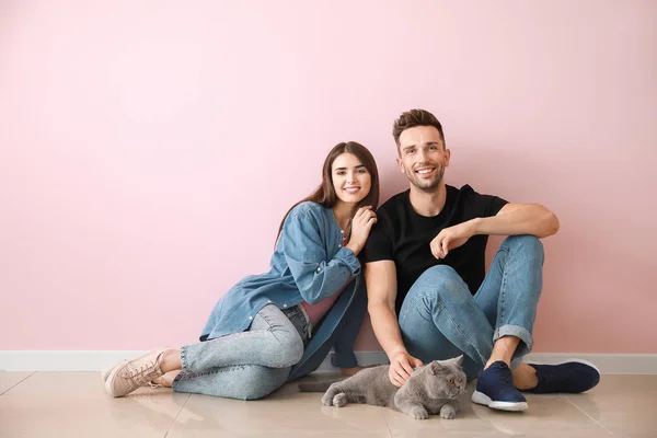 Happy couple with cute cat near color wall