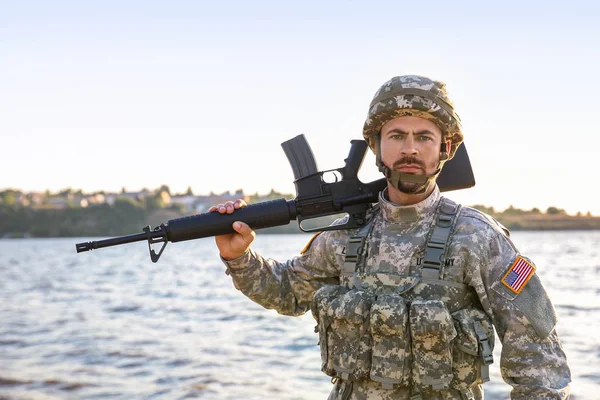 Soldato in mimetizzazione con fucile d'assalto vicino al fiume — Foto Stock