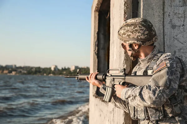 Soldat i camouflage tager sigte i baghold udendørs - Stock-foto