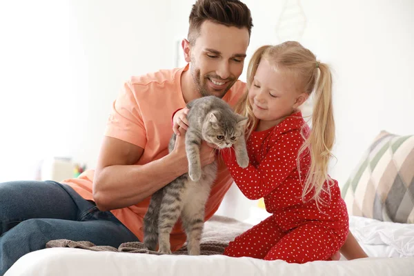 Buon padre e figlia con simpatico gatto sul letto a casa — Foto Stock