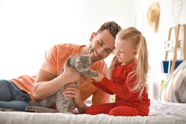 Happy father and daughter with cute cat on bed at home — Stock Photo, Image