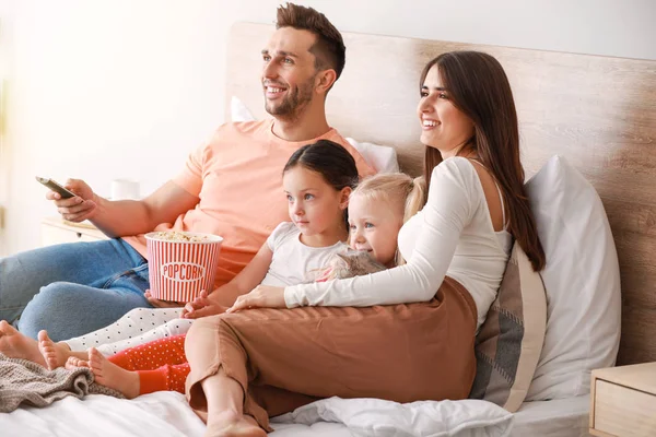 Happy family watching TV on bed at home