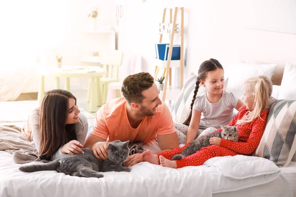 Happy family with cute cats on bed at home — Stock Photo, Image