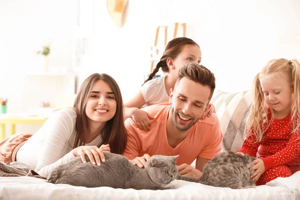 Happy family with cute cats on bed at home — Stock Photo, Image