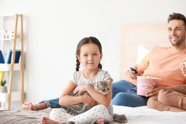 Bambina con gatto carino seduto sul letto a casa — Foto Stock