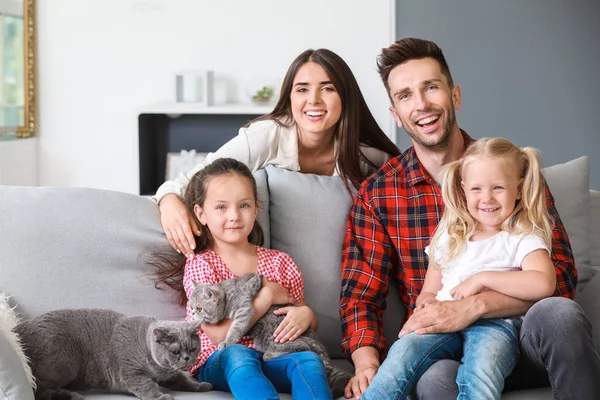 Família feliz com gatos bonitos descansando em casa — Fotografia de Stock