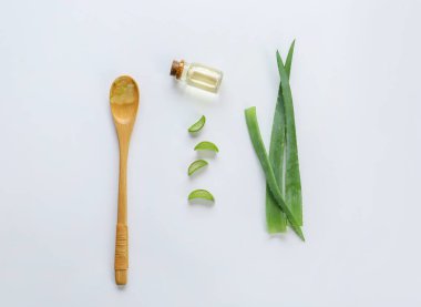 Beyaz arka plan üzerinde uçucu yağ ve kaşık ile Taze aloe yaprakları