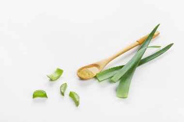 Beyaz arka plan üzerinde kaşıkile taze aloe yaprakları